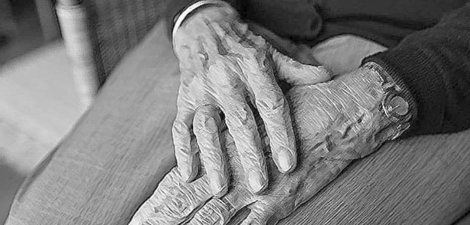 Schwarzweiße Grafik zeigt in Großaufnahme übereinander gelegte Hände mit Damenuhr an einem Handgelenk im Schoß einer betreuungsbedürftigen Seniorin - Haushaltshilfe Trittau